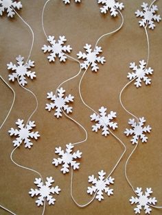 white snowflakes are strung up on brown paper