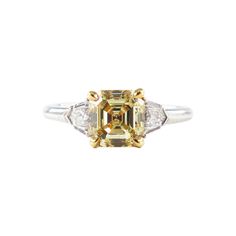 This exquisite piece by J. Birnbach combines classic style with a pop of color. The ring features a 1.94 carat GIA certified Fancy Yellow Asscher cut diamond, with a beautifully saturated color and lively sparkle. The yellow Asscher cut is set in 18K yellow gold, so the prongs blend in with the yellow of the stone. Two white shields (weighing 0.34 carats total) are the perfect accent, drawing the eye to the center stone and contrasting with the yellow of the Asscher cut. The ring is crafted in platinum and sits low to the hand. This unique ring is a sleek and sophisticated way to wear color, and would make a one of a kind engagement ring or right hand ring. Customization and sizing available. Asscher Cut Diamond Ring, Canary Yellow Diamonds, Asscher Engagement Ring, Asscher Cut Engagement Rings, Yellow Diamond Rings, Asscher Cut Diamond, Right Hand Rings, Diamond Anniversary Rings, Asscher Cut