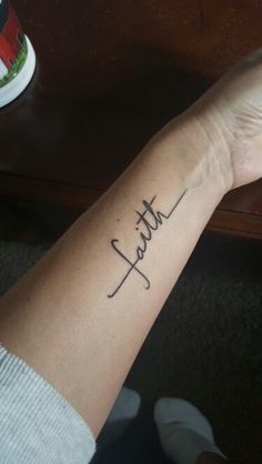 a woman's wrist with the word faith tattooed on her left arm, in cursive font