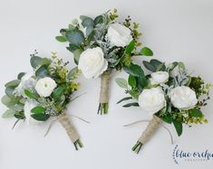 three bridal bouquets with white flowers and greenery are arranged on the wall