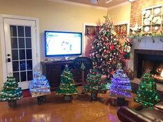 a living room decorated for christmas with lights on the trees and television in the fireplace