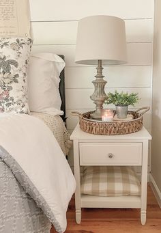 a white bed sitting next to a nightstand with a lamp on top of it