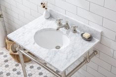 a bathroom sink sitting under a mirror next to a white tiled wall with hexagonal tiles