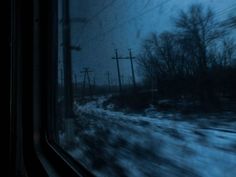 the view from a train window on a snowy day with power lines in the distance