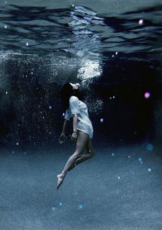 a woman is floating in the water with her legs spread out