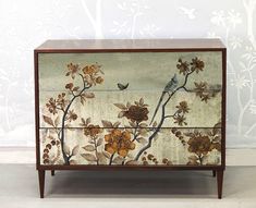 an old dresser with flowers painted on the front and side panels, sitting against a wall