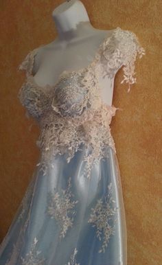 a dress is displayed on a mannequin with white lace and blue satin material