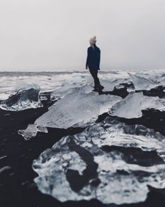 a man standing on top of an ice covered beach