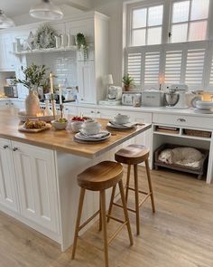 a kitchen with two stools in front of the island and plates on the counter