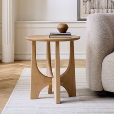 a wooden table sitting on top of a white rug next to a couch in a living room