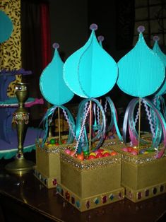 three paper umbrellas sitting on top of cardboard boxes with candy in front of them