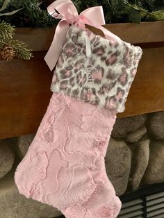 a pink stocking hanging from a mantel decorated with pineconi and leopard print