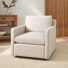 a white chair sitting on top of a rug in front of a wooden cabinet and shelf