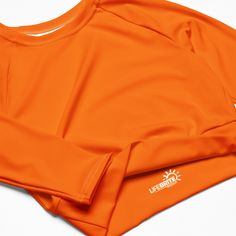 Fall in love with this versatile piece of eye-catching activewear. Our eco-friendly always bright orange cropped rash guard –made with recycled polyester and elastane– is the perfect choice for swimming, sports, or athleisure outfits. The long sleeves and cropped cut provides just enough coverage while the UPF 50+ rated material helps block the sun’s harsh UV rays. Stand out in confidence and comfort all year long in our “wear anywhere” cropped top. .: Made with 81% REPREVE recycled polyester, 1 Fitted Orange Gym Tops, Fitted Orange Top For Gym, Orange Yoga Tops, Orange Stretch Yoga Tops, Stretch Orange Yoga Tops, Orange Stretch Tops For Yoga, Orange Fitted Workout Tops, Sporty Orange Fitted Swimwear, Fitted Orange Workout Tops