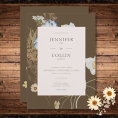 a wedding card with flowers on the front and back, sitting on a wooden table