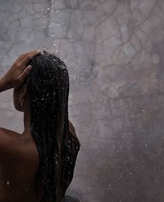 a woman standing in the rain with her hair back and wet hands on her head