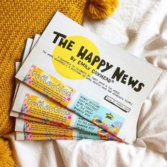 the happy news paper is laying on top of some other newspaper papers and a yellow pom - pom