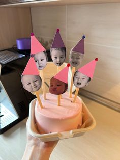 a person holding up a cake with photos on it in the shape of birthday hats