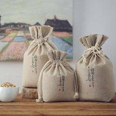 three bags of rice sitting on top of a wooden table next to a white bowl