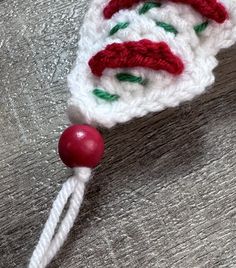 a white crocheted hat with red and green beads