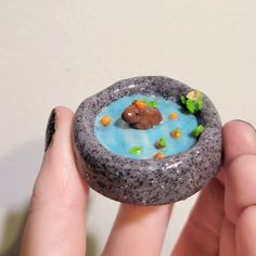 a person holding a small toy in the shape of a rock with a bear on it