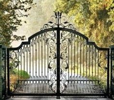 an iron gate is open in front of some trees