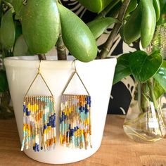 a pair of earrings sitting on top of a table next to a potted plant