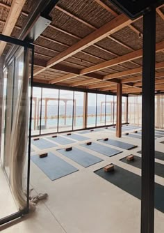 an empty room with yoga mats on the floor and large windows looking out onto the water