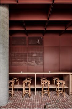 the inside of a restaurant with wooden tables and stools in front of red walls