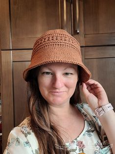 a woman wearing a brown hat standing in front of wooden cabinets