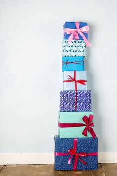 a stack of wrapped presents sitting on top of each other in front of a wall