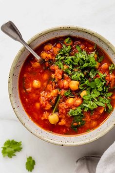 a white bowl filled with chickpea soup and garnished with cilantro