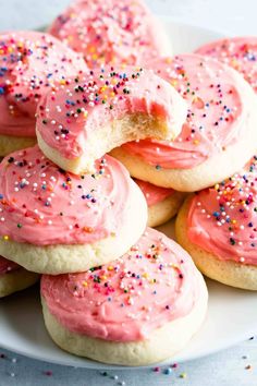 pink frosted sugar cookies with sprinkles on a white plate, ready to be eaten