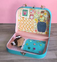 an open suitcase with a stuffed animal in it on a wooden floor next to a pink wall