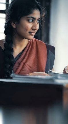 a woman sitting at a table with a plate in her hand and looking off to the side