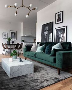 a living room with green couches and pictures on the wall above it's coffee table