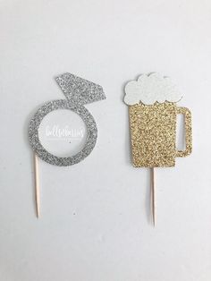 two cupcake toppers with glitter on them, one has a beer and the other has a number