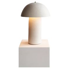 a white table lamp sitting on top of a wooden block