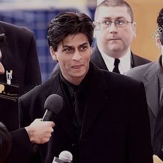 two men in suits and one is holding a microphone