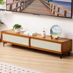 a flat screen tv mounted on the wall above a wooden entertainment center with two planters