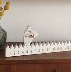 a wooden ruler sitting on top of a table next to a vase with flowers