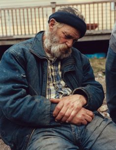 an old man with a beard sitting on the ground