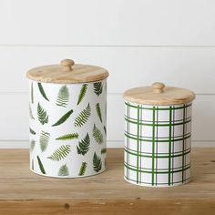 two green and white canisters sitting on top of a wooden table