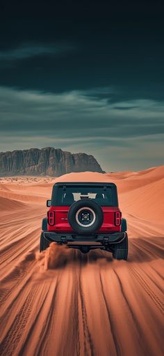 a red jeep driving through the desert