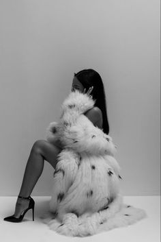 a woman sitting on the ground wearing a fur coat