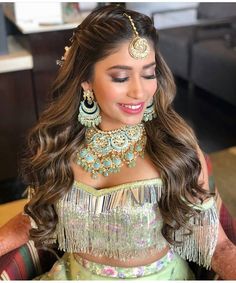 a beautiful woman in a green outfit with gold jewelry and earrings on her head is smiling at the camera