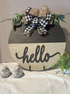 a wooden sign with the word hello hanging from it's side and two little birds sitting next to it