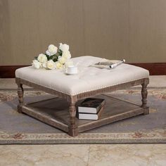 a coffee table with white flowers on top and a book in the middle sitting on a rug