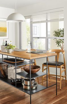 a kitchen island with two chairs and a table in front of the window, on top of a hard wood floor