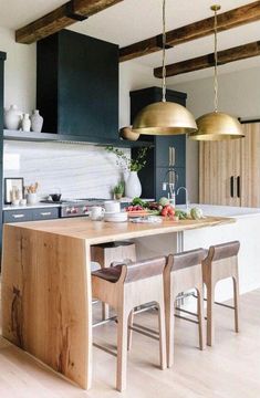 an island in the middle of a kitchen with stools and lights hanging from it